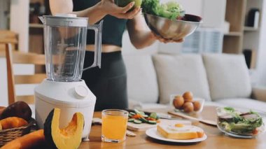 Beyaz tişörtlü ve siyah şapkalı kadın mutfakta taze meyve suyu hazırlıyor.