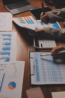 Group of confident business people point to graphs and charts to analyze market data, balance sheet, account, net profit to plan new sales strategies to increase production capacity.