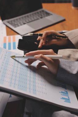 Group of confident business people point to graphs and charts to analyze market data, balance sheet, account, net profit to plan new sales strategies to increase production capacity.