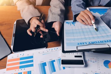 Group of confident business people point to graphs and charts to analyze market data, balance sheet, account, net profit to plan new sales strategies to increase production capacity.