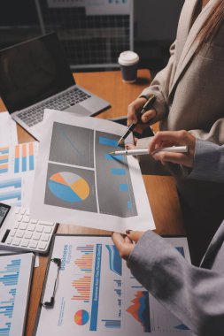 Group of confident business people point to graphs and charts to analyze market data, balance sheet, account, net profit to plan new sales strategies to increase production capacity.