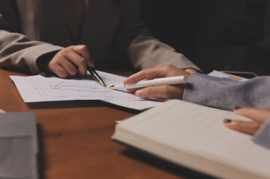 Group of confident business people point to graphs and charts to analyze market data, balance sheet, account, net profit to plan new sales strategies to increase production capacity.