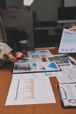 Group of confident business people point to graphs and charts to analyze market data, balance sheet, account, net profit to plan new sales strategies to increase production capacity.