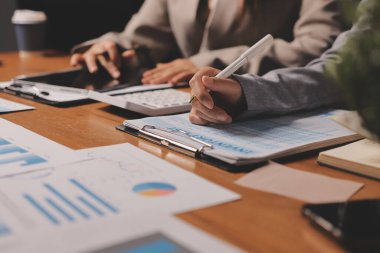 Group of confident business people point to graphs and charts to analyze market data, balance sheet, account, net profit to plan new sales strategies to increase production capacity.