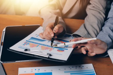 Group of confident business people point to graphs and charts to analyze market data, balance sheet, account, net profit to plan new sales strategies to increase production capacity.