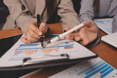 Group of confident business people point to graphs and charts to analyze market data, balance sheet, account, net profit to plan new sales strategies to increase production capacity.