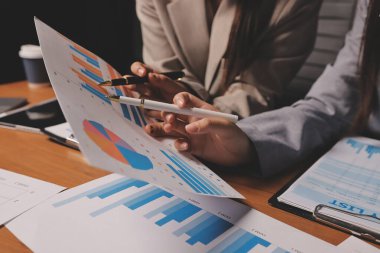 Group of confident business people point to graphs and charts to analyze market data, balance sheet, account, net profit to plan new sales strategies to increase production capacity.