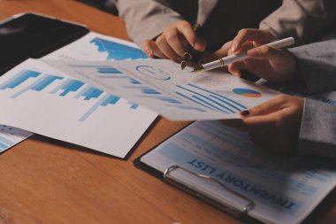 Group of confident business people point to graphs and charts to analyze market data, balance sheet, account, net profit to plan new sales strategies to increase production capacity.