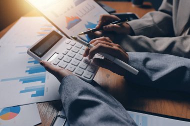 Group of confident business people point to graphs and charts to analyze market data, balance sheet, account, net profit to plan new sales strategies to increase production capacity.