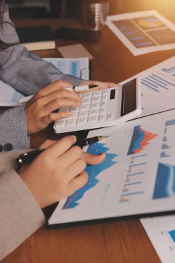 Group of confident business people point to graphs and charts to analyze market data, balance sheet, account, net profit to plan new sales strategies to increase production capacity.