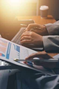 Group of confident business people point to graphs and charts to analyze market data, balance sheet, account, net profit to plan new sales strategies to increase production capacity.