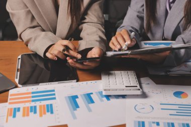 Group of confident business people point to graphs and charts to analyze market data, balance sheet, account, net profit to plan new sales strategies to increase production capacity.