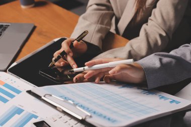 Group of confident business people point to graphs and charts to analyze market data, balance sheet, account, net profit to plan new sales strategies to increase production capacity.