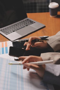 Group of confident business people point to graphs and charts to analyze market data, balance sheet, account, net profit to plan new sales strategies to increase production capacity.