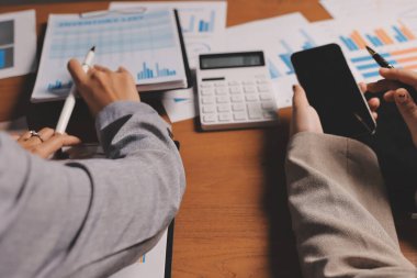 Group of confident business people point to graphs and charts to analyze market data, balance sheet, account, net profit to plan new sales strategies to increase production capacity.