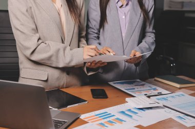 Group of confident business people point to graphs and charts to analyze market data, balance sheet, account, net profit to plan new sales strategies to increase production capacity.