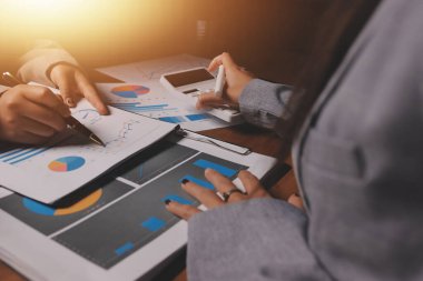 Group of confident business people point to graphs and charts to analyze market data, balance sheet, account, net profit to plan new sales strategies to increase production capacity.