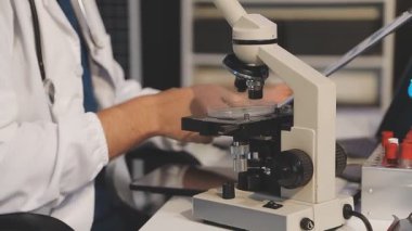 Yakın plan - mikroskop tutan ve laboratuvarda kan inceleyen bilim adamları.