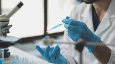 Laboratuvarda laboratuvar örnekleriyle çalışan koruyucu eldivenler giyen bilim adamı.