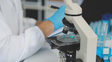 Yakın plan - laboratuvarda mikroskop tutan bilim adamlarının elleri