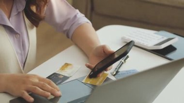 Kartvizit tutan ve evinde online ödeme için dizüstü bilgisayar kullanan kadın.