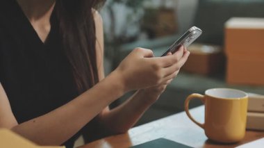 Ofiste akıllı telefonla çalışan bir kadın.