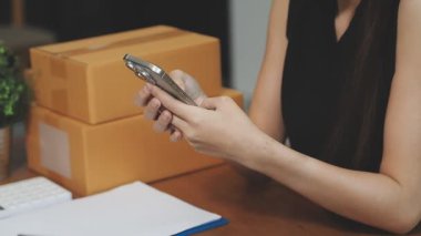 İş kadını elinde bir akıllı telefon tutuyor, mesaj gönderiyor, masadan mesaj gönderiyor, dizüstü bilgisayar kullanıyor..