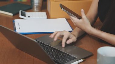 Evde dizüstü bilgisayar ve cep telefonuyla çalışan bir kadın.