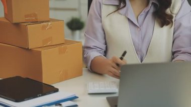 İş, insan ve teknoloji kavramı - Laptop bilgisayarı ve ofis arka planında kutuları olan kadınlara yakın çekim