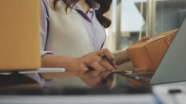 Ofiste elinde dizüstü bilgisayar olan ve dijital tablet kullanan kadın.