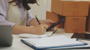 Ofisteki kadın girişimci dizüstü bilgisayarda çalışıyor ve masadaki belgeleri kontrol ediyor..