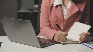 Ofiste belgelerle ve bilgisayarla çalışan iş kadını..