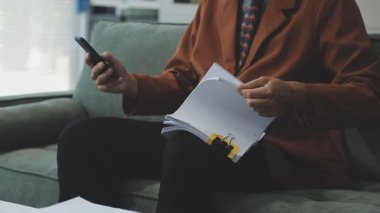 Üst düzey iş adamları ofis odasında otururken mali raporları okuyorlar.