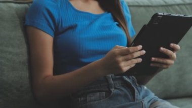 Yakın plan. Oturma odasında dijital tablet kullanan genç bir kadın..