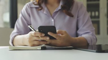 Ofiste cep telefonu kullanan genç bir kadın..