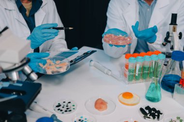 Laboratuvardaki Asyalı bilim adamları mikroskop ve laboratuvar ekipmanları kullanarak gıda araştırmaları yapıyor, gıda bilimi ve biyoteknoloji alanında yenilikler sergiliyorlar.