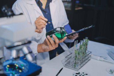 Laboratuvardaki Asyalı bilim adamları mikroskop ve laboratuvar ekipmanları kullanarak gıda araştırmaları yapıyor, gıda bilimi ve biyoteknoloji alanında yenilikler sergiliyorlar.