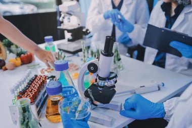 Laboratuvardaki Asyalı bilim adamları mikroskop ve laboratuvar ekipmanları kullanarak gıda araştırmaları yapıyor, gıda bilimi ve biyoteknoloji alanında yenilikler sergiliyorlar.