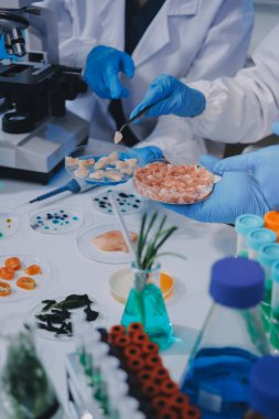 Laboratuvardaki Asyalı bilim adamları mikroskop ve laboratuvar ekipmanları kullanarak gıda araştırmaları yapıyor, gıda bilimi ve biyoteknoloji alanında yenilikler sergiliyorlar.