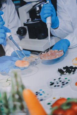 Laboratuvardaki Asyalı bilim adamları mikroskop ve laboratuvar ekipmanları kullanarak gıda araştırmaları yapıyor, gıda bilimi ve biyoteknoloji alanında yenilikler sergiliyorlar.