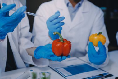 Laboratuvardaki Asyalı bilim adamları mikroskop ve laboratuvar ekipmanları kullanarak gıda araştırmaları yapıyor, gıda bilimi ve biyoteknoloji alanında yenilikler sergiliyorlar.