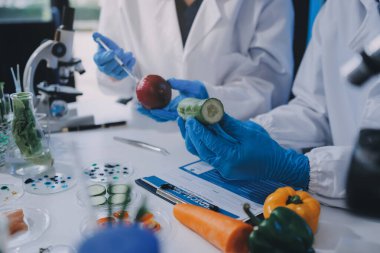 Laboratuvardaki Asyalı bilim adamları mikroskop ve laboratuvar ekipmanları kullanarak gıda araştırmaları yapıyor, gıda bilimi ve biyoteknoloji alanında yenilikler sergiliyorlar.