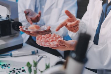 Laboratuvardaki Asyalı bilim adamları mikroskop ve laboratuvar ekipmanları kullanarak gıda araştırmaları yapıyor, gıda bilimi ve biyoteknoloji alanında yenilikler sergiliyorlar.