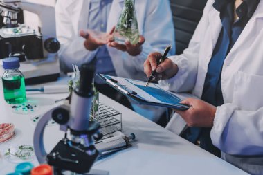 Laboratuvardaki Asyalı bilim adamları mikroskop ve laboratuvar ekipmanları kullanarak gıda araştırmaları yapıyor, gıda bilimi ve biyoteknoloji alanında yenilikler sergiliyorlar.