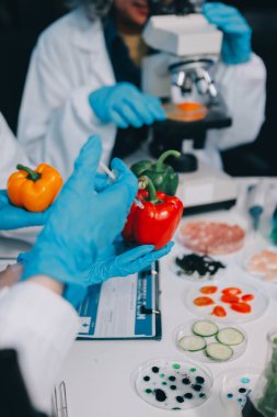 Laboratuvardaki Asyalı bilim adamları mikroskop ve laboratuvar ekipmanları kullanarak gıda araştırmaları yapıyor, gıda bilimi ve biyoteknoloji alanında yenilikler sergiliyorlar.