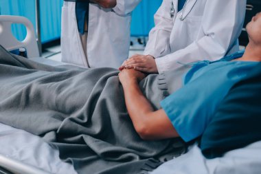 Hemşire yatağında hastalık olan yaşlı bir hastaya yardım ediyor. Tıbbi asistan ve doktor hastane koğuşunda oksijen tüplü ve serum torbalı emekliler için sağlık kontrolü yapıyorlar..