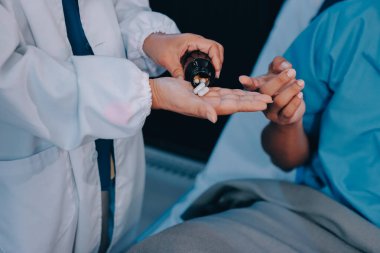 Hemşire yatağında hastalık olan yaşlı bir hastaya yardım ediyor. Tıbbi asistan ve doktor hastane koğuşunda oksijen tüplü ve serum torbalı emekliler için sağlık kontrolü yapıyorlar..