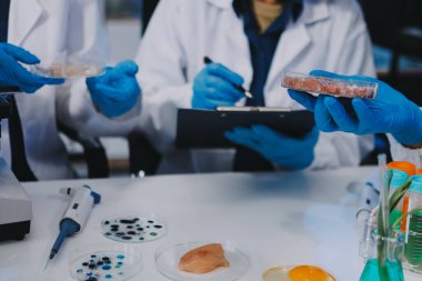 Laboratuvardaki Asyalı bilim adamları mikroskop ve laboratuvar ekipmanları kullanarak gıda araştırmaları yapıyor, gıda bilimi ve biyoteknoloji alanında yenilikler sergiliyorlar.