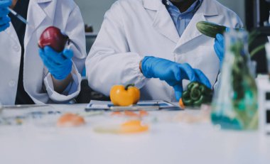Laboratuvardaki Asyalı bilim adamları mikroskop ve laboratuvar ekipmanları kullanarak gıda araştırmaları yapıyor, gıda bilimi ve biyoteknoloji alanında yenilikler sergiliyorlar.