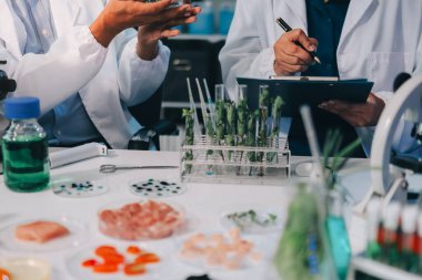 Laboratuvardaki Asyalı bilim adamları mikroskop ve laboratuvar ekipmanları kullanarak gıda araştırmaları yapıyor, gıda bilimi ve biyoteknoloji alanında yenilikler sergiliyorlar.